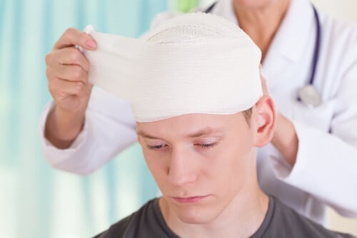 Doctor unwrapping bandage from young man's head. Contact a brain injury lawyer at Englander Peebles.
