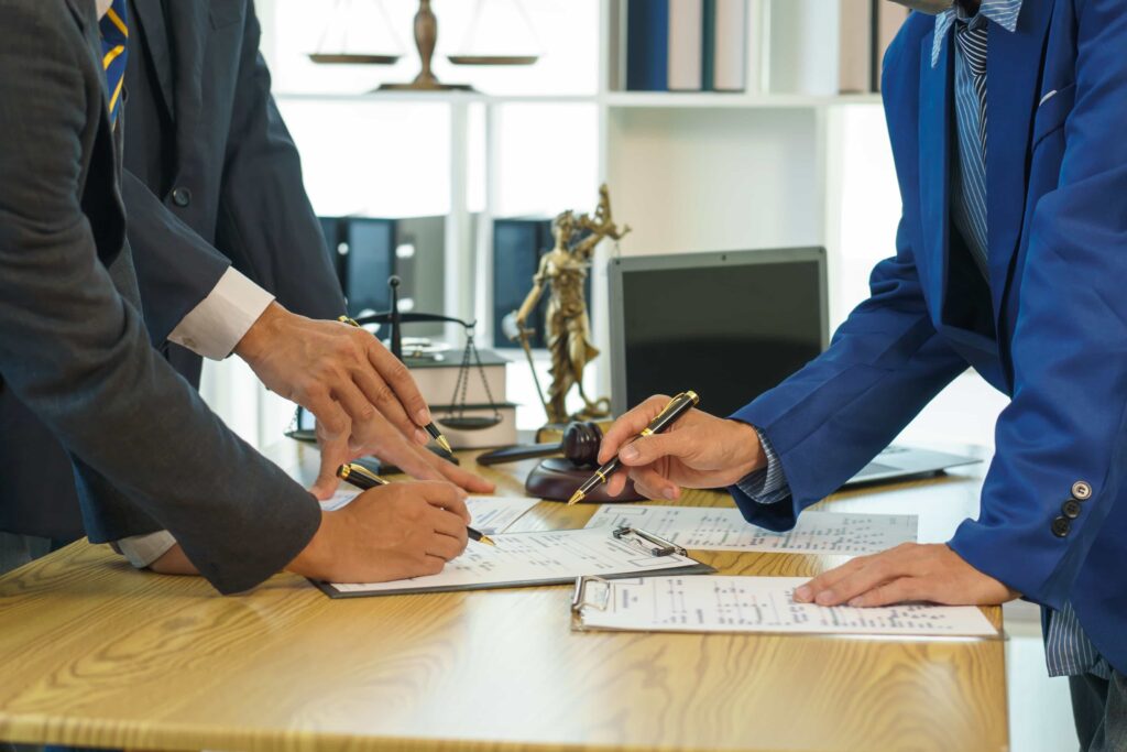 Team of lawyers reviewing legal documents together in law office with justice scales and gavel on desk.