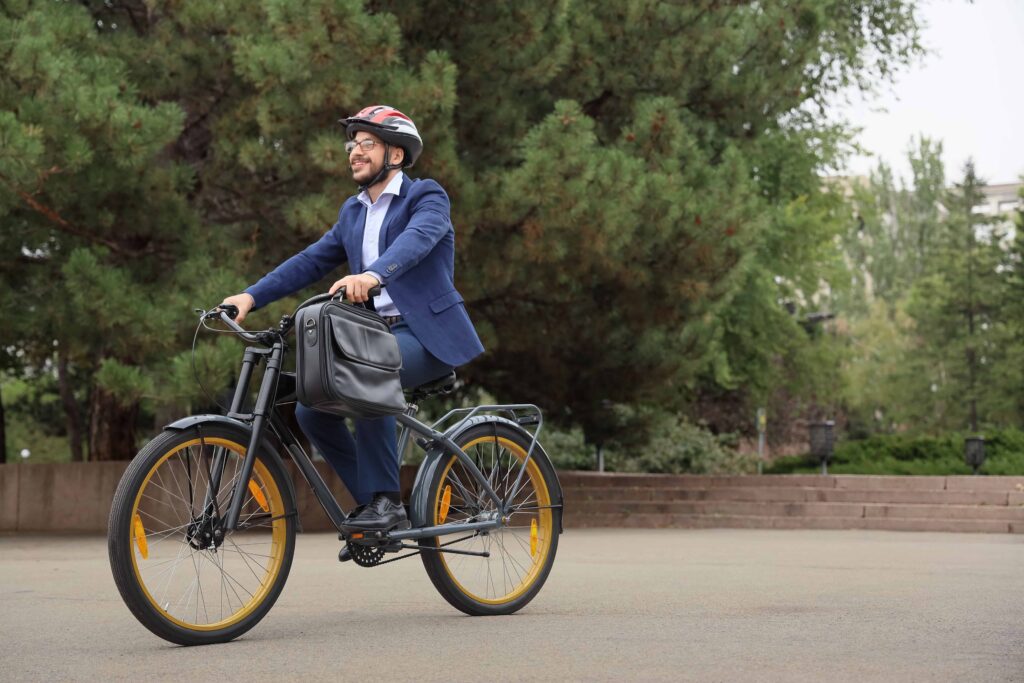 Smiling businessman in suit riding bicycle with helmet and briefcase outdoors. Smiling businessman in suit riding bicycle with helmet and briefcase outdoors.