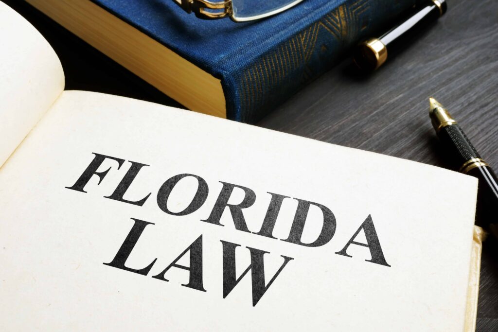 Open book displaying &ldquo;Florida Law&rdquo; with legal books and a pen on a desk, representing Florida legal statutes and state law reference.